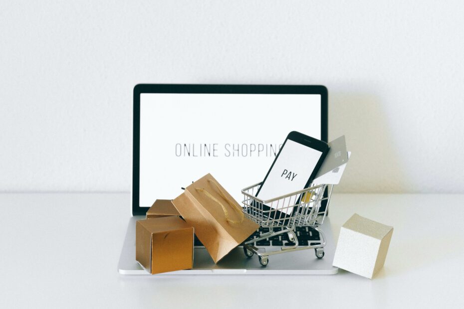 Beitragsbild für Pflichtangaben im E-Commerce: Laptop, Smartphone in Einkaufswagen, Pakete